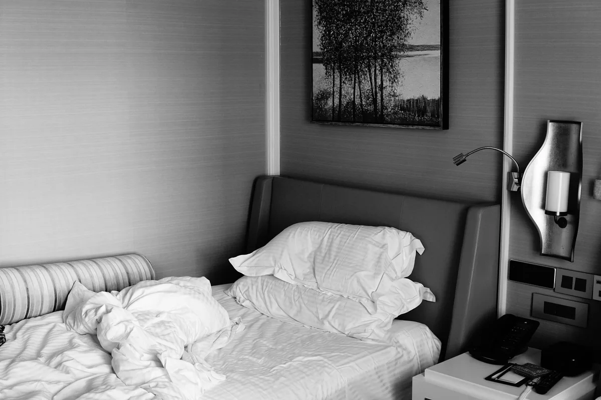 Chambre d'hôtel en désordre avec des objets personnels éparpillés sur le lit et le sol