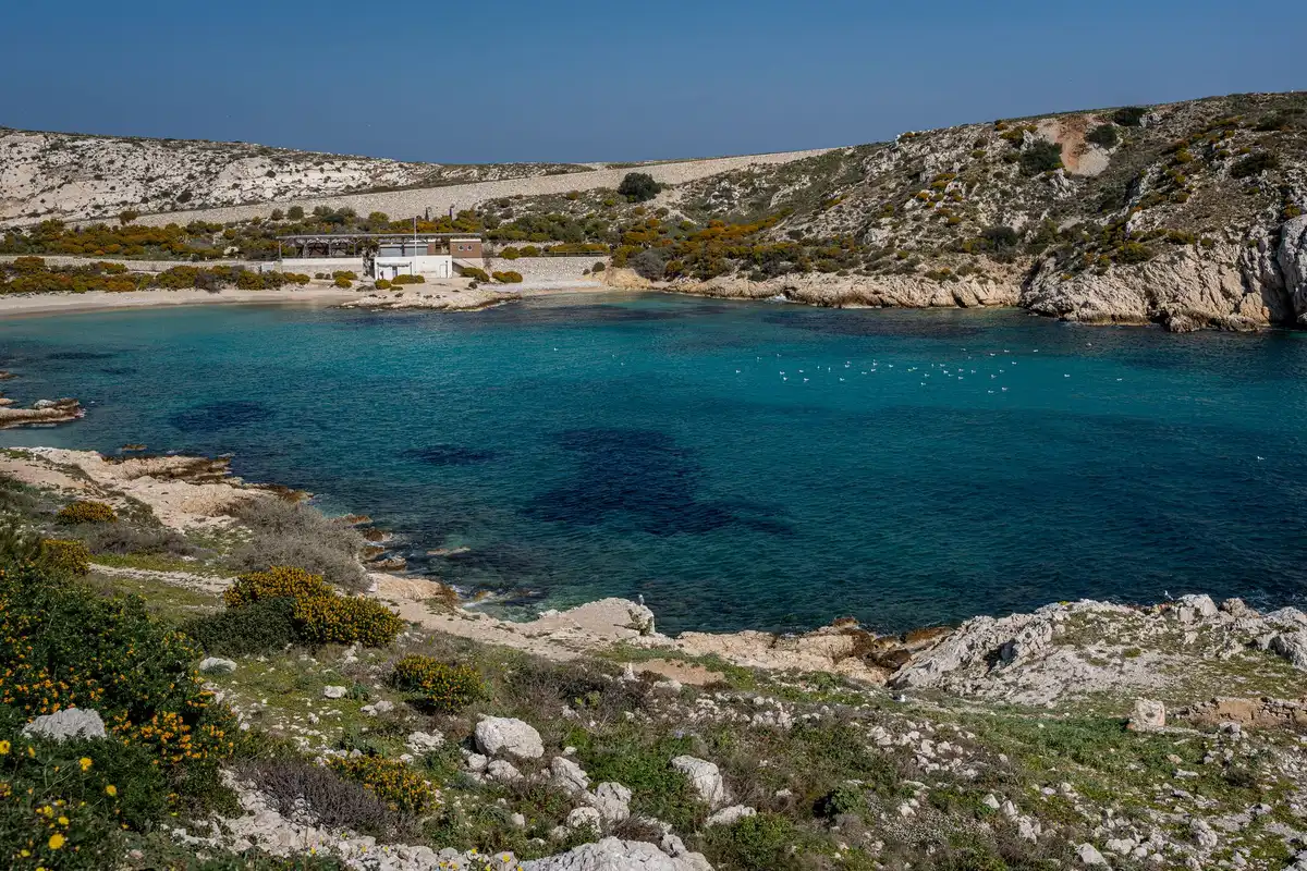 Petite calanque méditerranéenne avec eau turquoise et falaises calcaires.