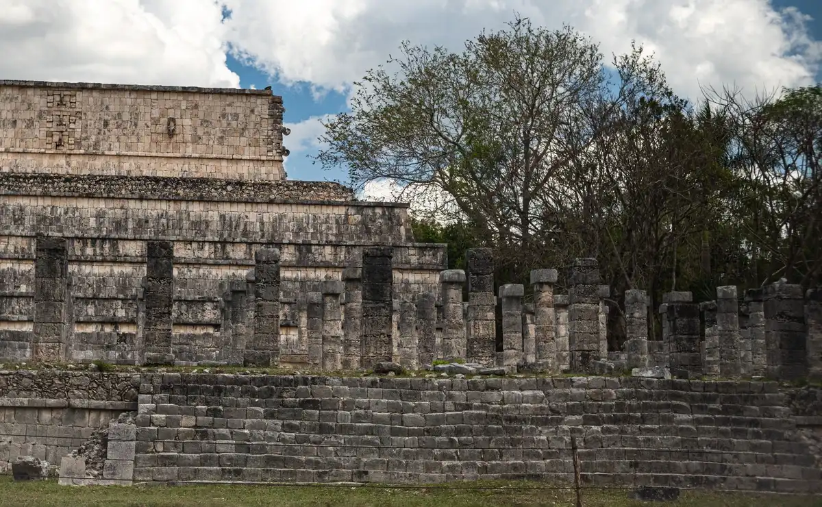 Ruines mayas avec sculptures et façades restaurées dans un paysage de collines basses