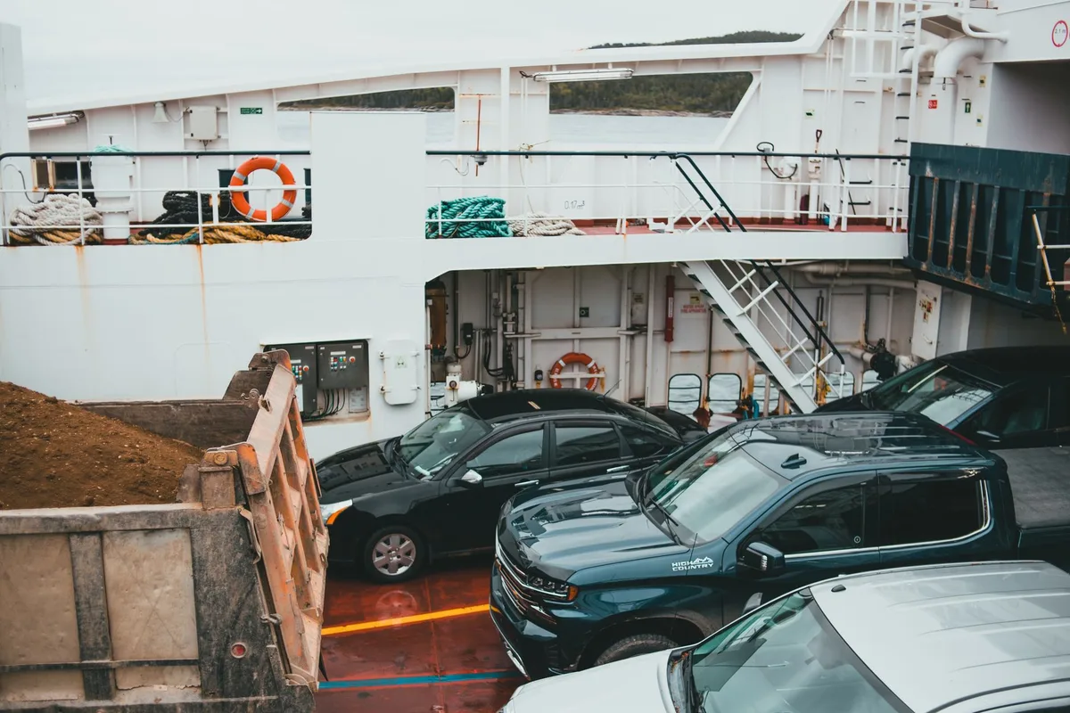 Voiture embarquant sur un ferry avec personnel du port et marquages au sol