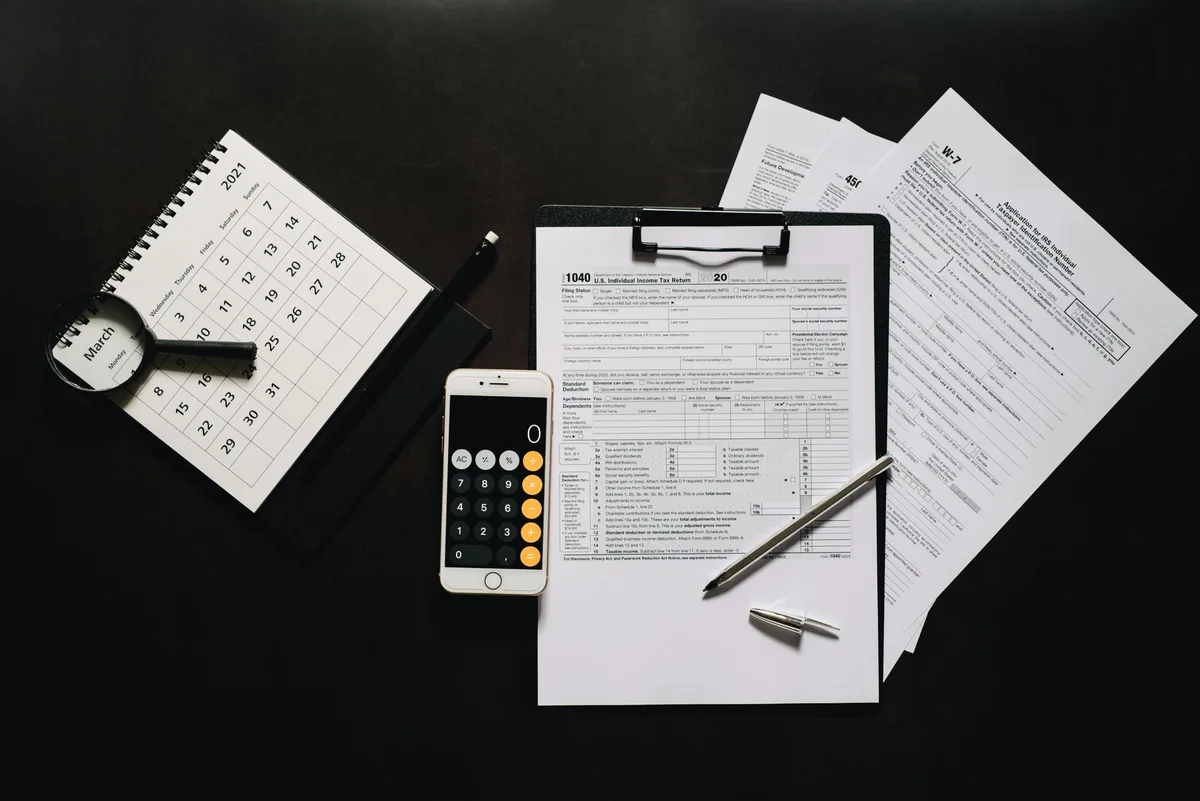Formulaires fiscaux et justificatifs sur un bureau avec calculatrice et stylo