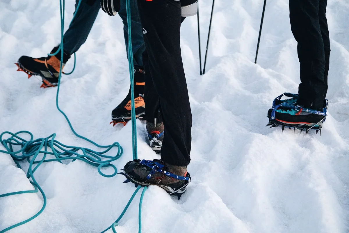 Équipement de trekking montagne : chaussures de randonnée, crampons, sac de couchage et vêtements en couches.