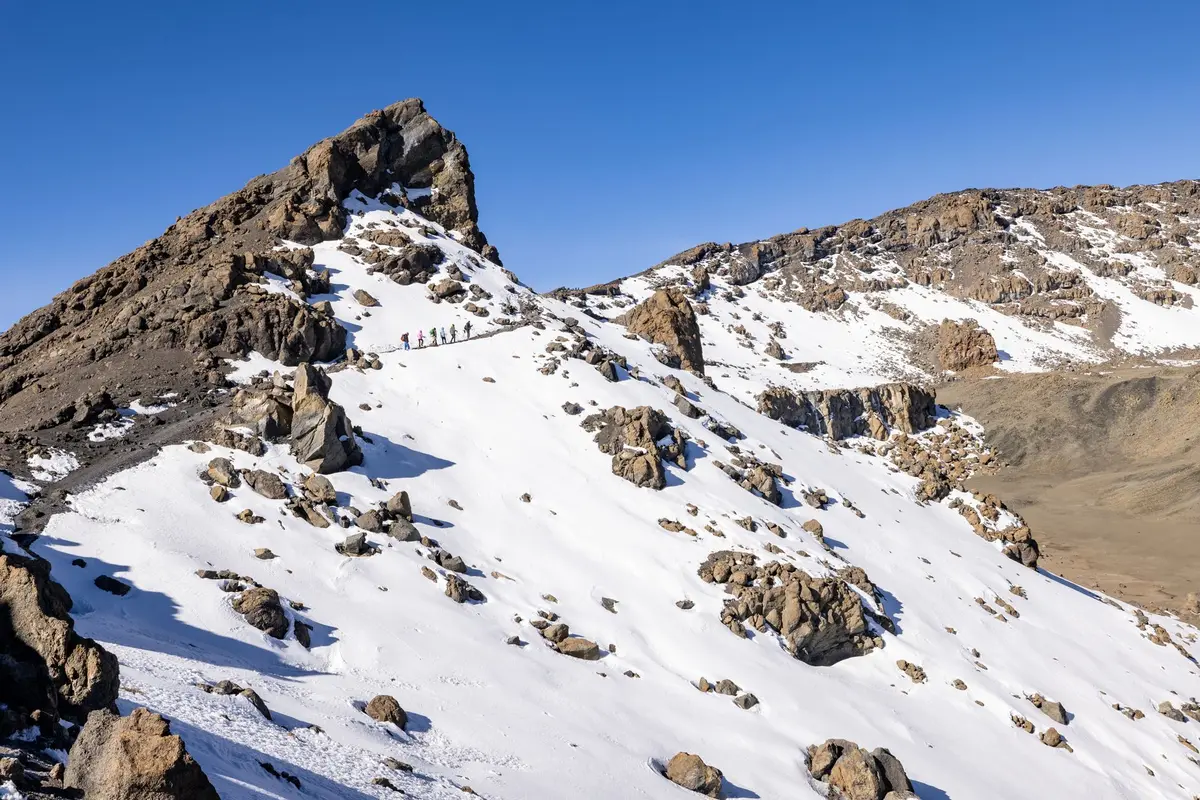 Sommet enneigé du Kilimandjaro avec randonneurs en ascension