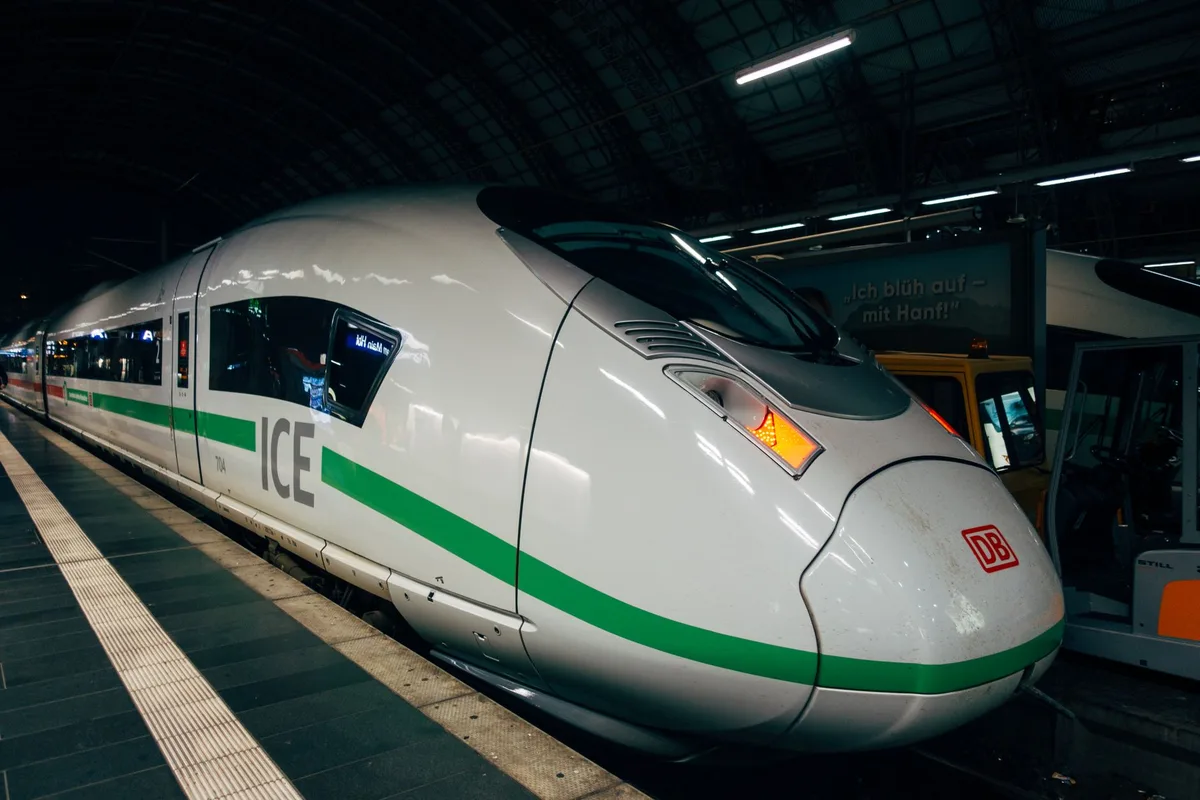 Gare de train moderne avec voyageurs et panneaux de départ en Europe