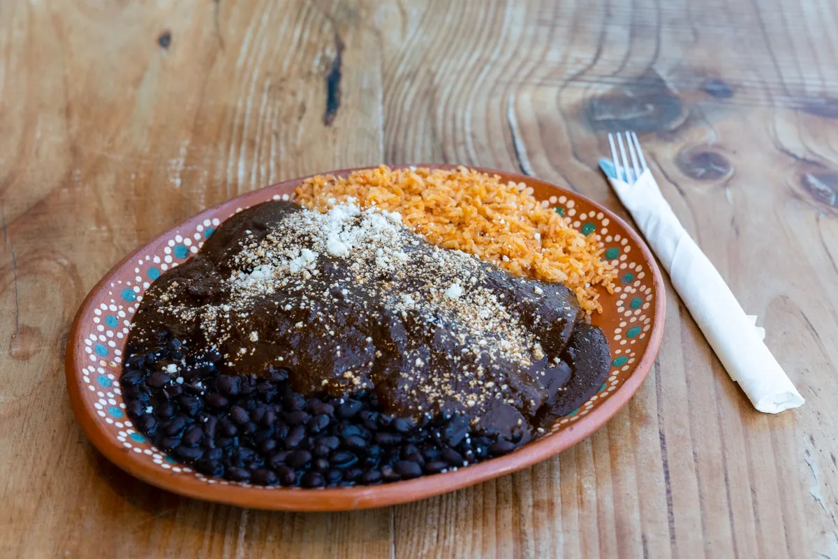 Préparation du mole poblano dans une cuisine traditionnelle mexicaine avec ustensiles en terre cuite.