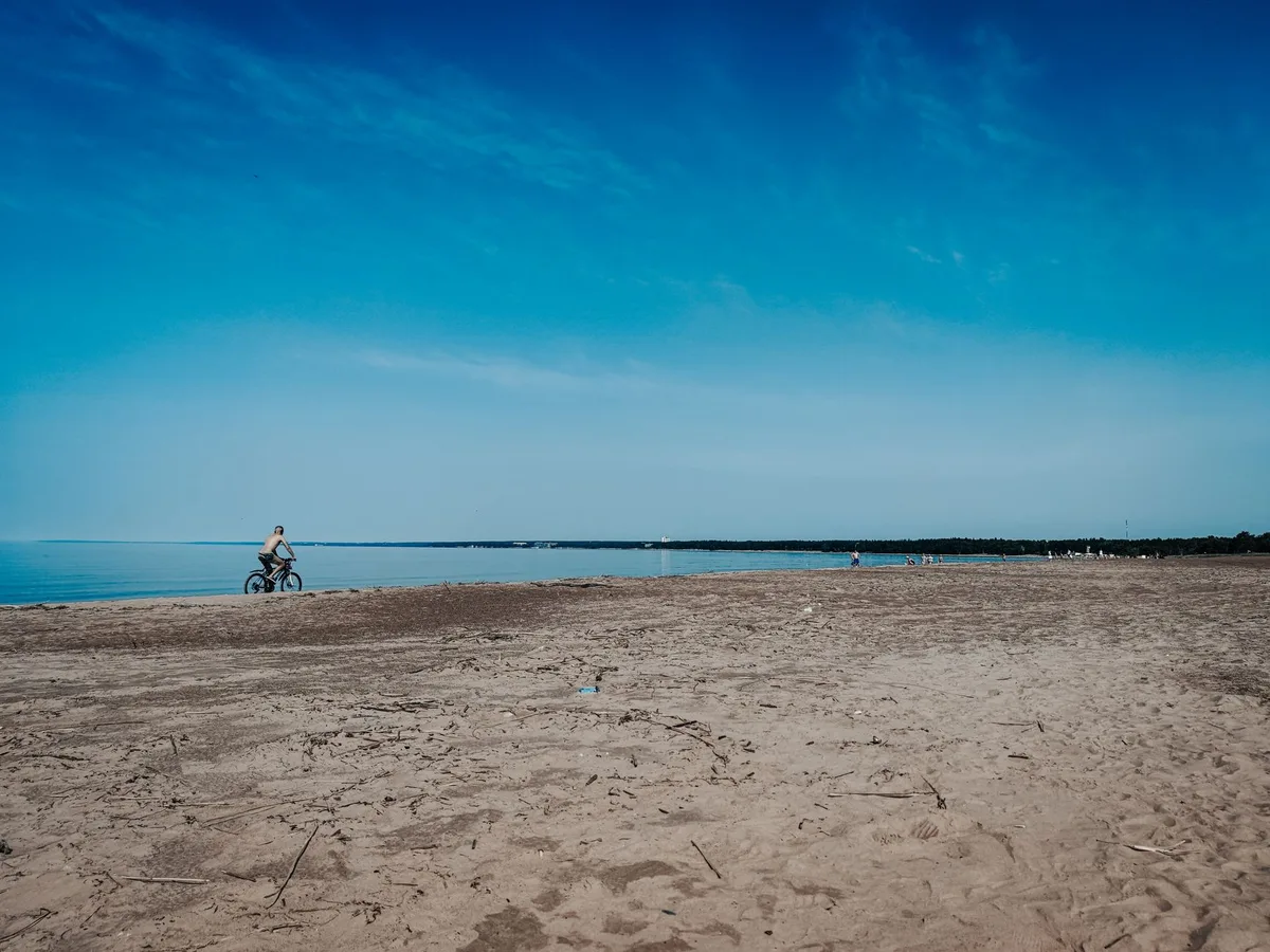 Piste cyclable longeant une baie avec plage et falaises en arrière-plan