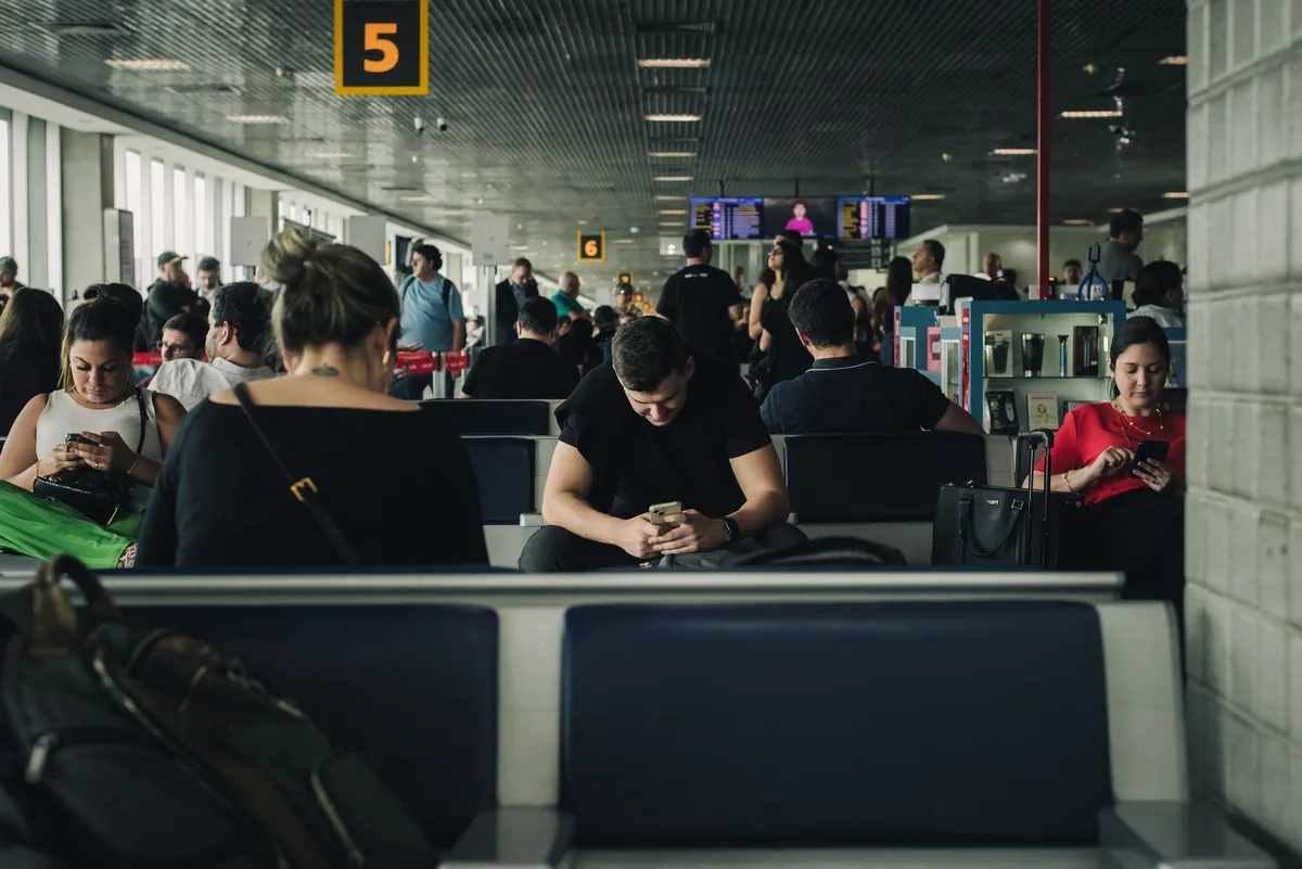 Passager consultant son téléphone à l'aéroport pour contacter la compagnie aérienne