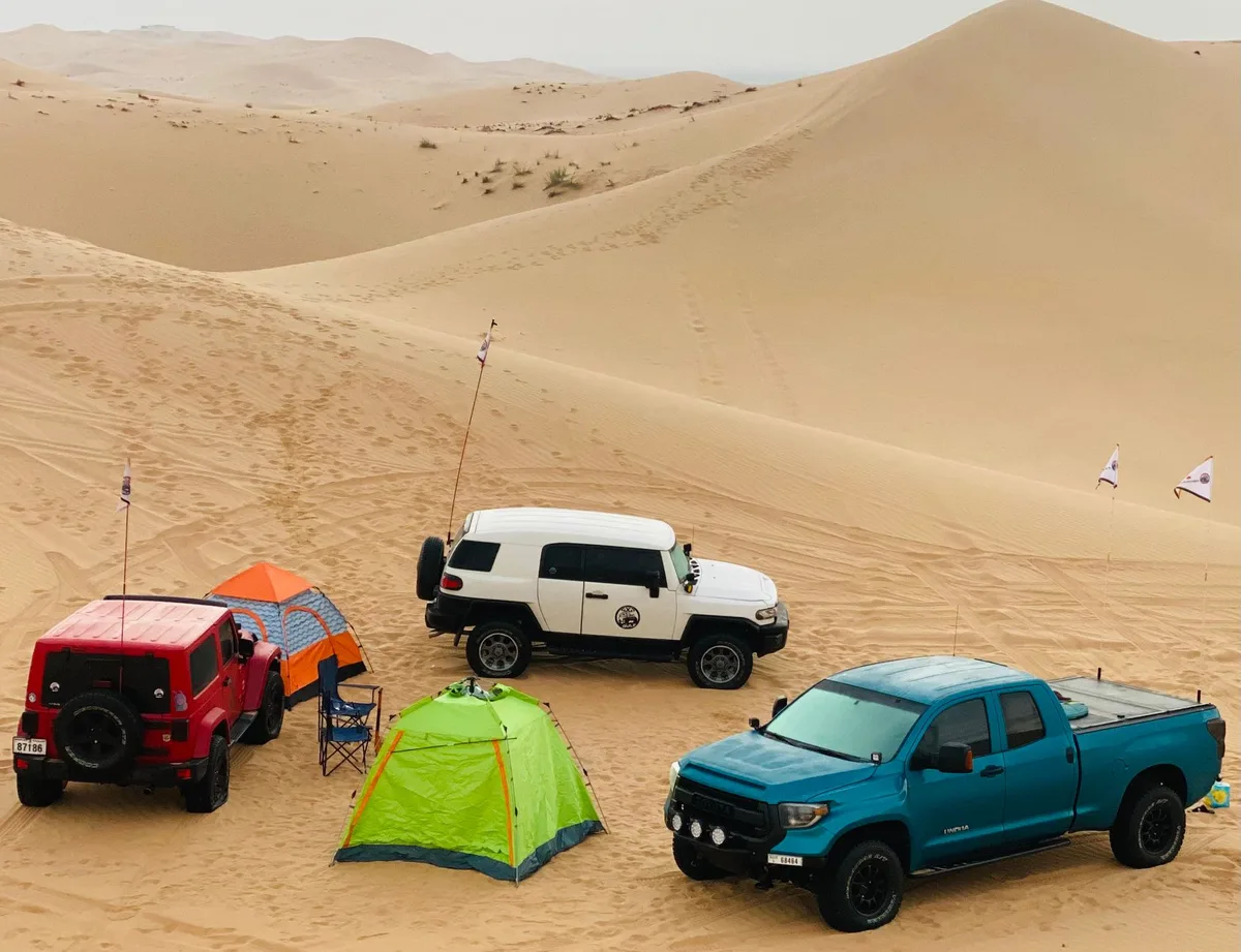 Un 4x4 équipé avec tente de toit et matériel de camping pour un autotour en terrain désertique