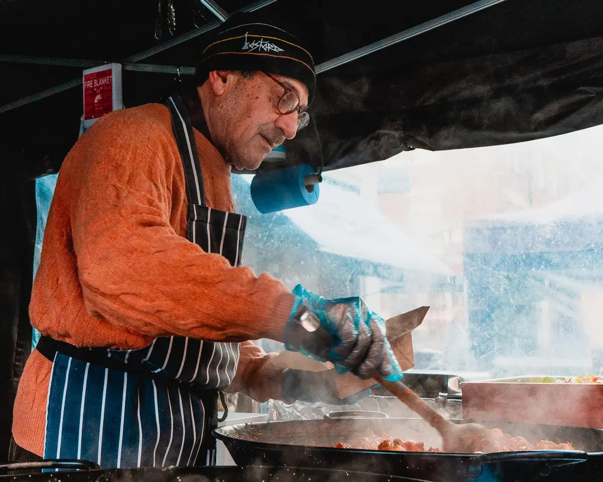 Vendeur de street food préparant un plat à la wok avec de la vapeur s'échappant du récipient