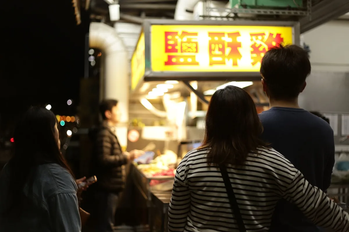 File d'attente de clients locaux devant un stand de street food animé en Asie