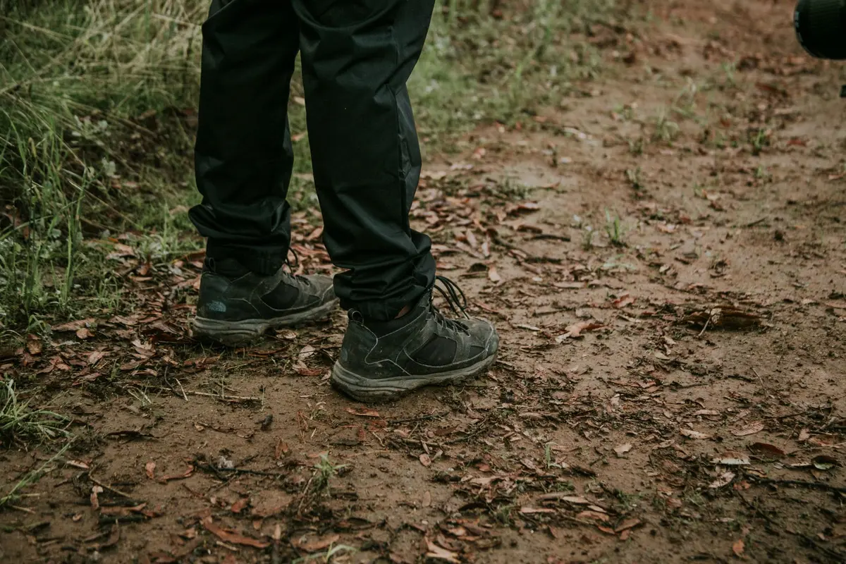 Chaussures de randonnée imperméables sur un sentier forestier boueux et humide.