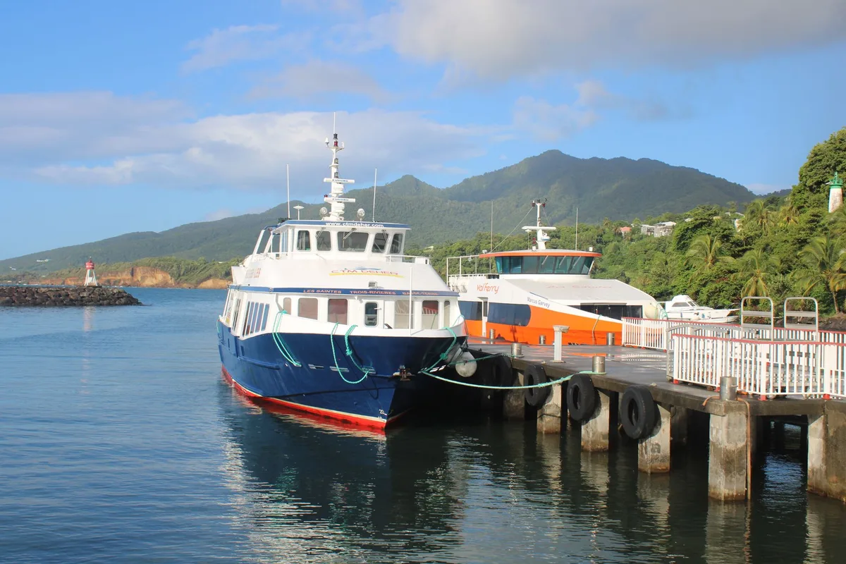 Bateau de ferry amarré à un quai tropical avec des passagers embarquant