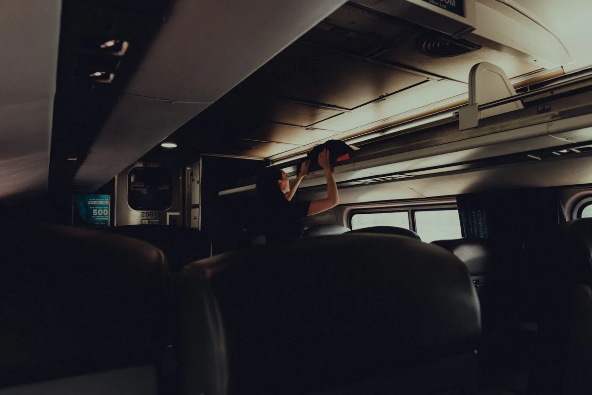 Voyageur rangeant ses bagages dans le compartiment supérieur d'un train de longue distance