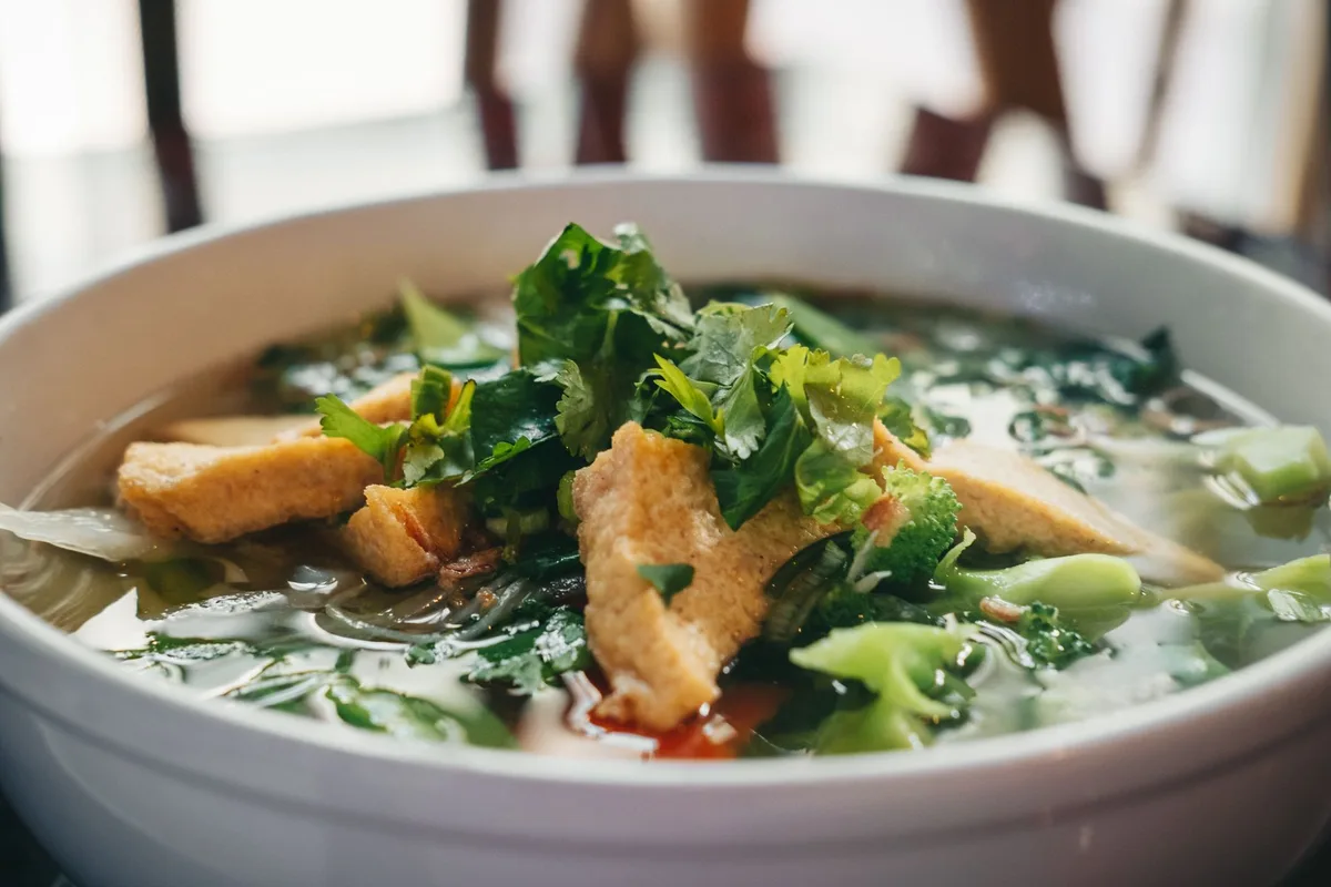 Bol de phở chay avec nouilles, tofu et bouillon de légumes garni d'herbes fraîches