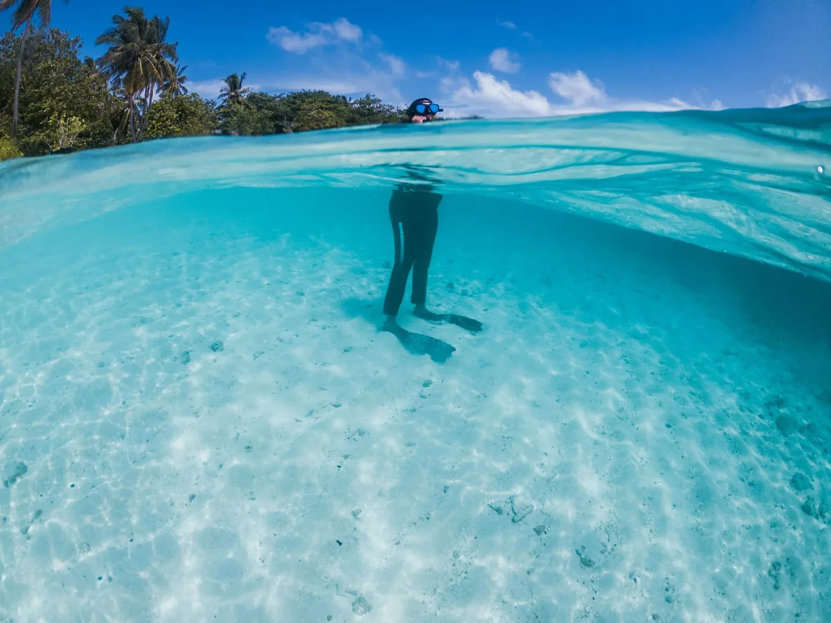 Plongeur en apnée dans les eaux turquoise d'un lagon tropical des Îles Cook