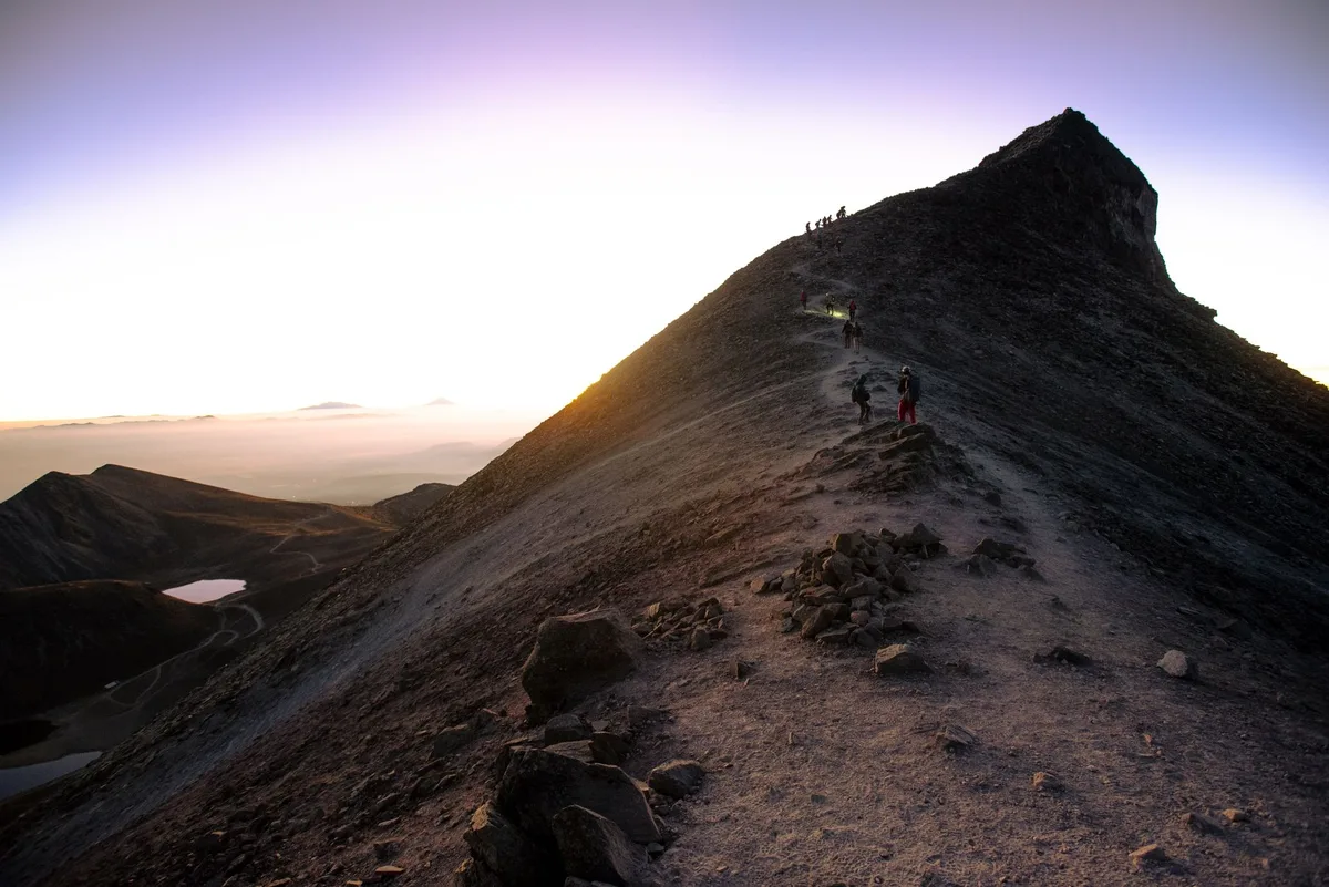 Sentier de randonnée en montagne au lever du soleil avec brume matinale sur les pentes