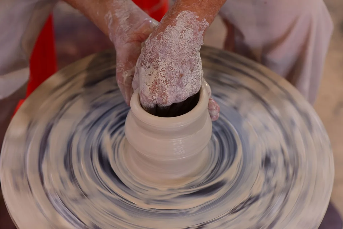 Artisan façonnant l'argile à la main dans un atelier de céramique