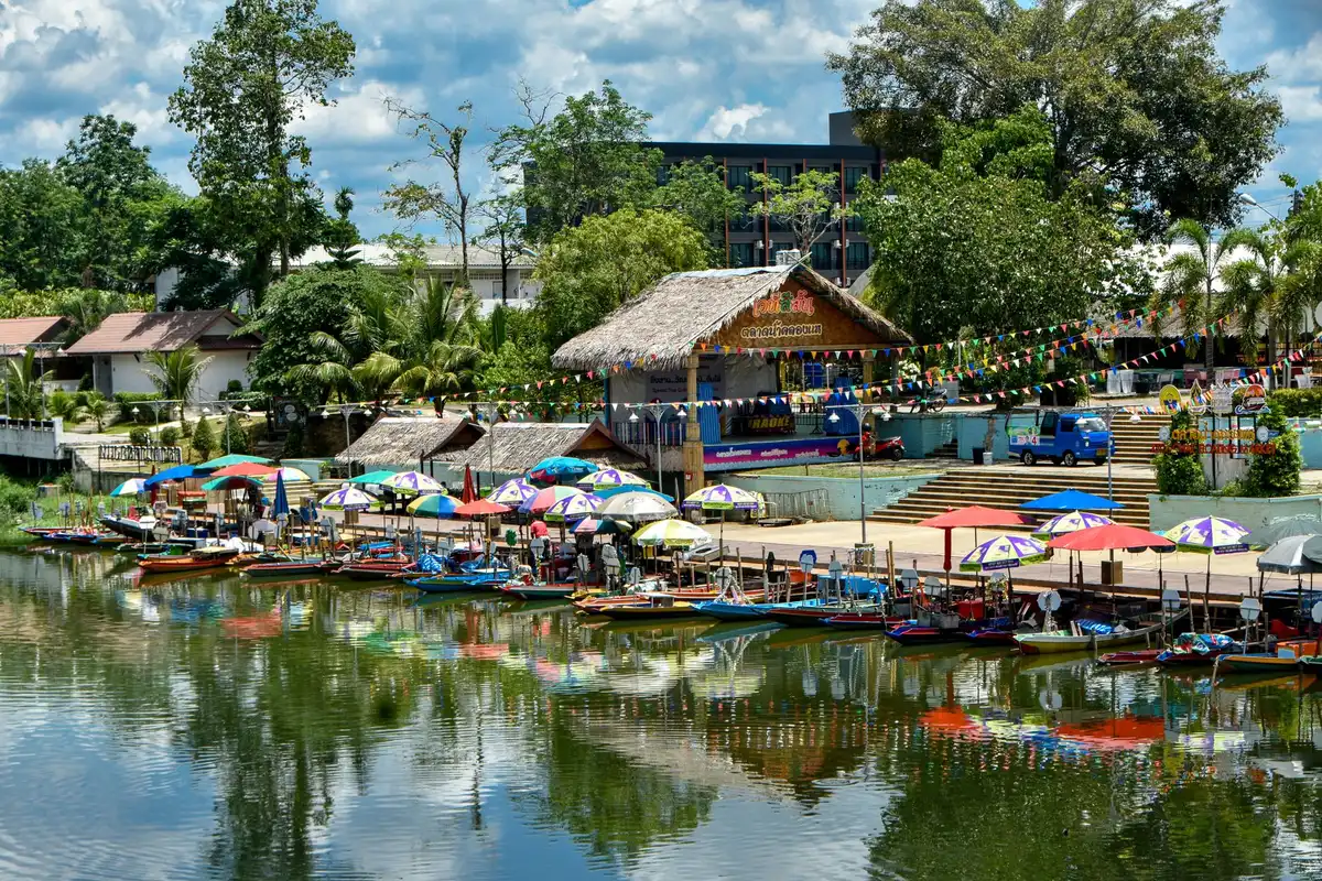 Marché d'antiquités animé au bord d'un canal avec bâtiments colorés et embarcations