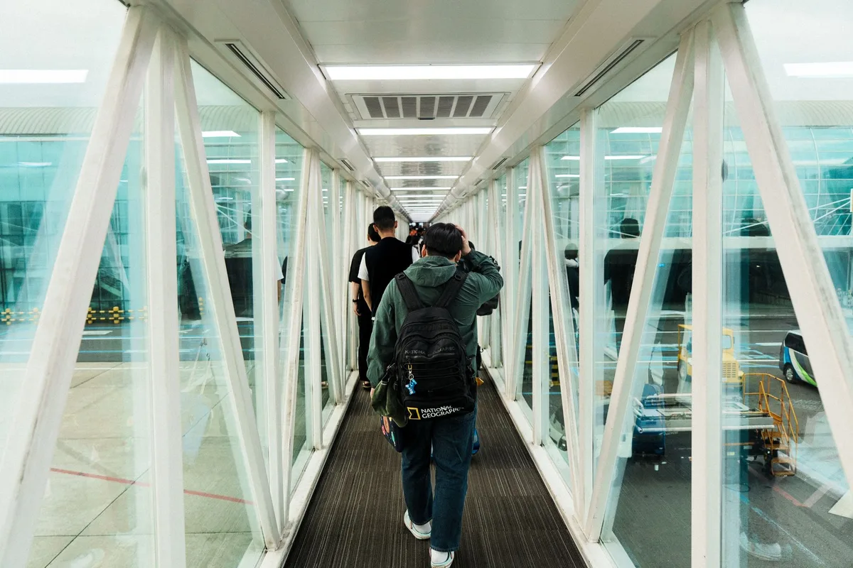 Mains d'une personne tenant une carte d'embarquement à un comptoir d'aéroport avec affichage d'annulation de vol