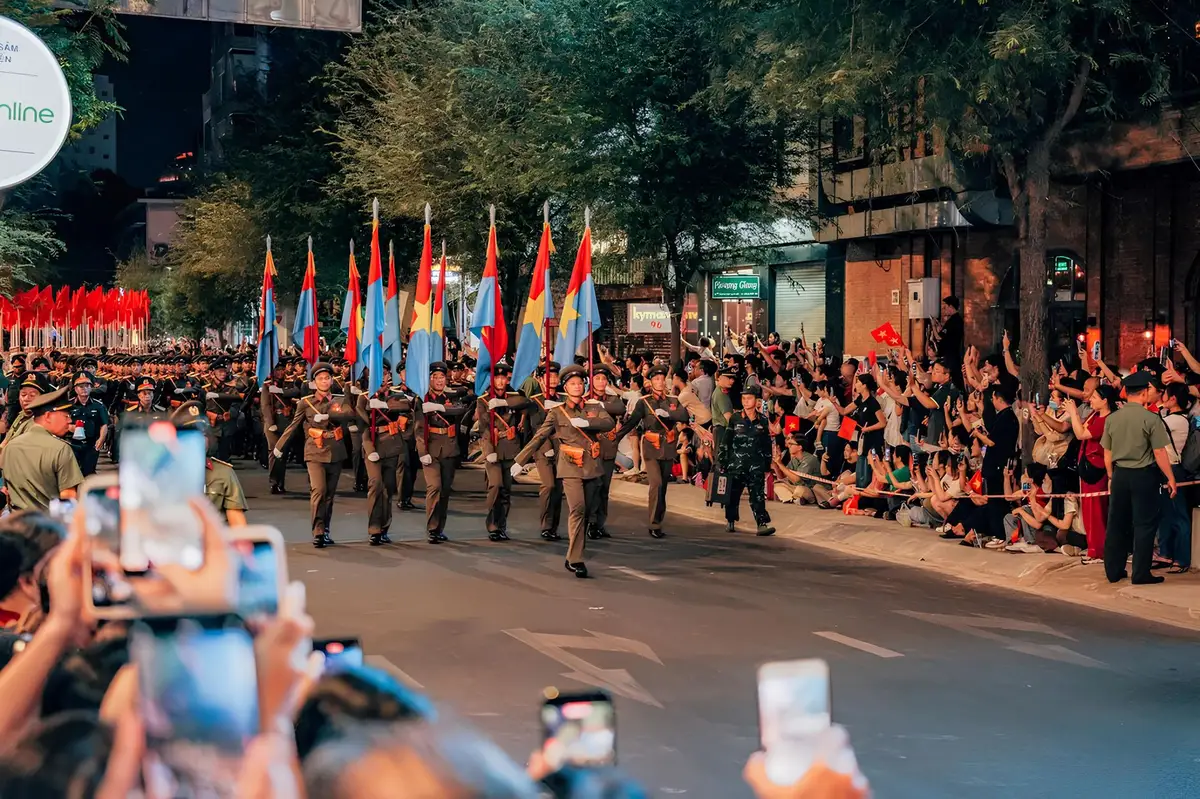 Foule de participants à une marche des fiertés urbaine avec drapeaux arc-en-ciel et ambiance festive.