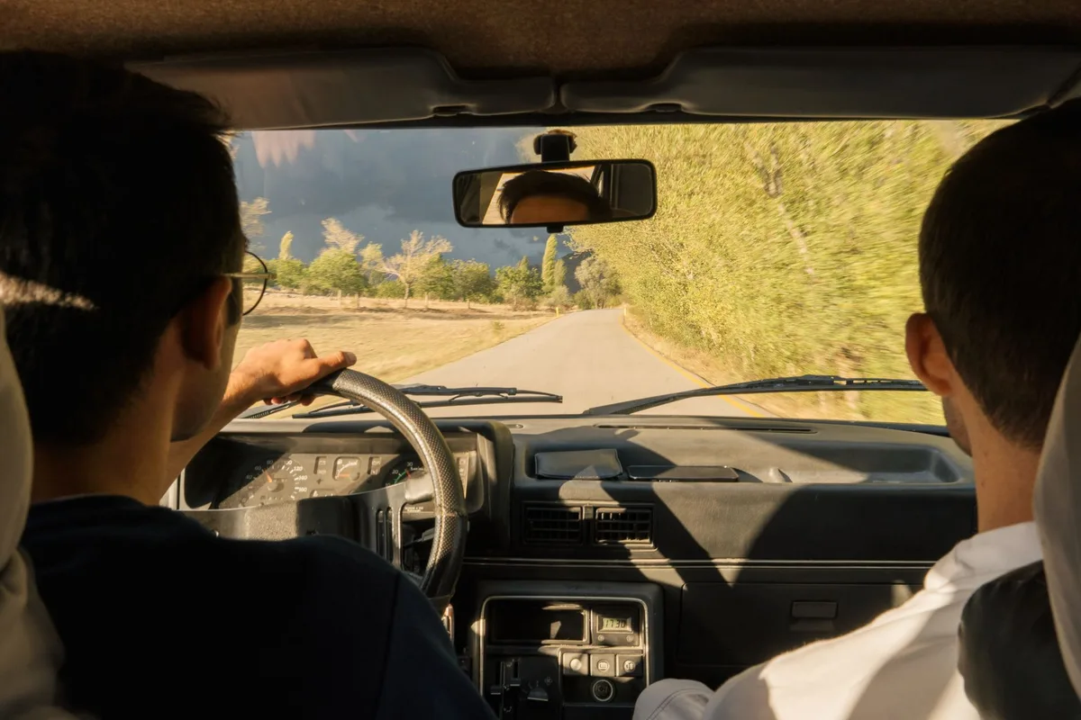 Intérieur d'une voiture de location avec volant et tableau de bord lors d'un road trip