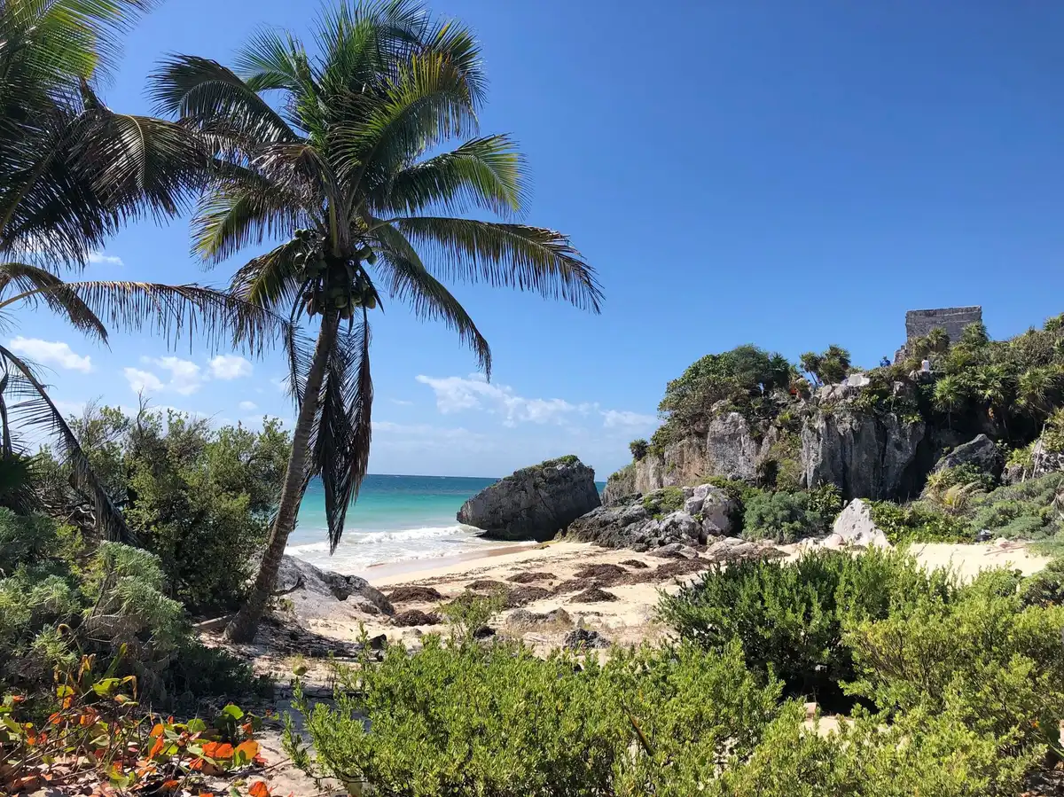 Plage turquoise avec ruines mayas visibles au-dessus des falaises à Tulum