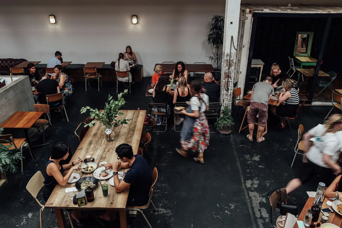 Petit restaurant local avec tables simples et ambiance conviviale, clientèle mixte
