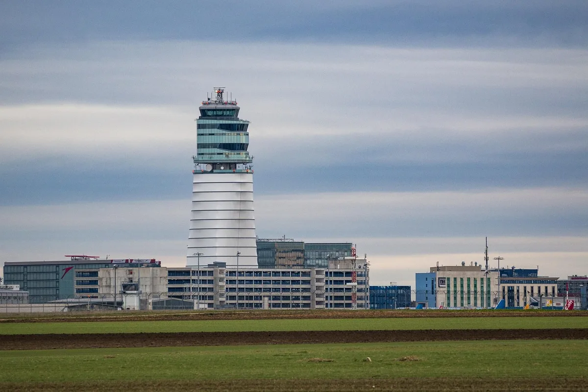 Hall d'aéroport en journée avec voyageurs et panneaux de départ