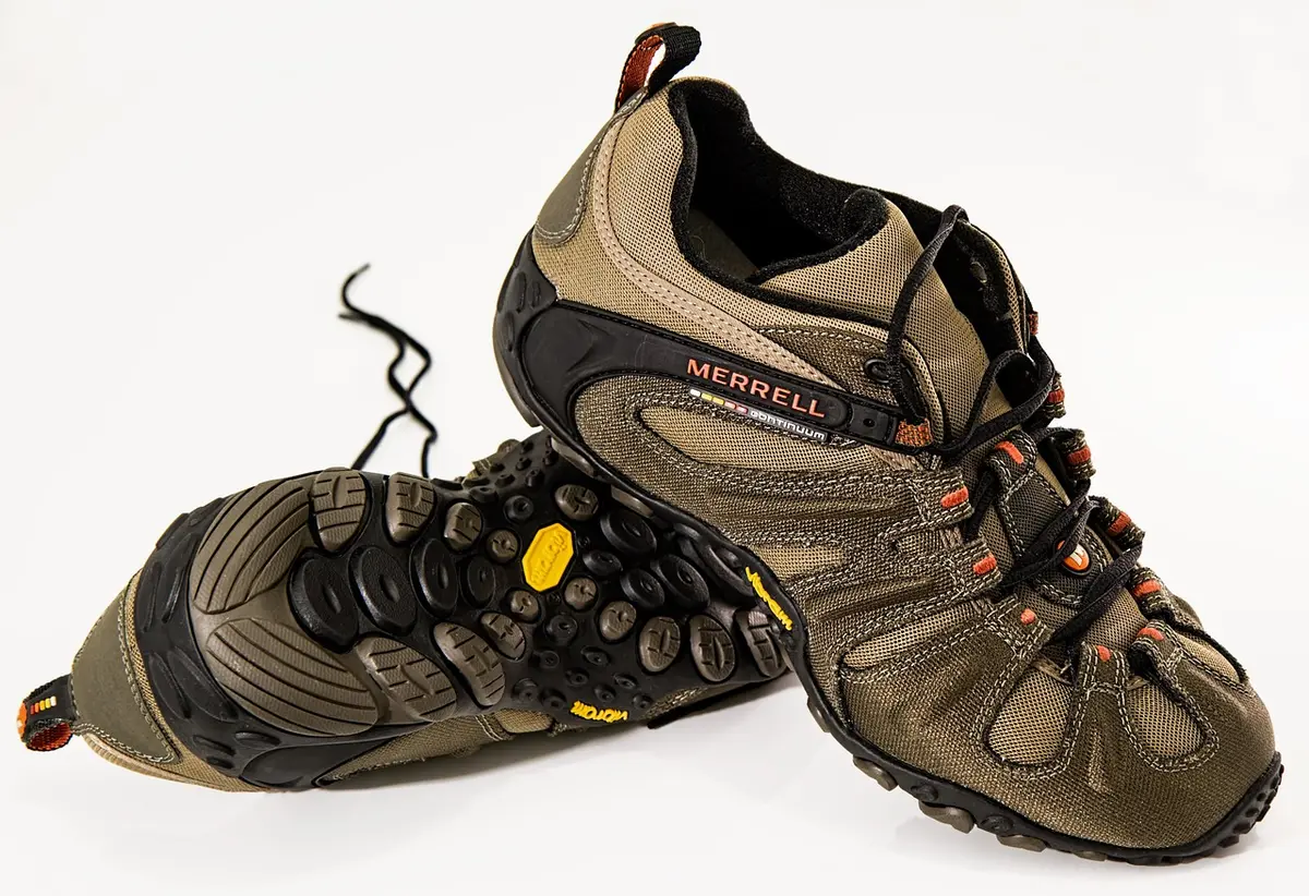 Personne ajustant des chaussures de randonnée au début d’un sentier en plein jour