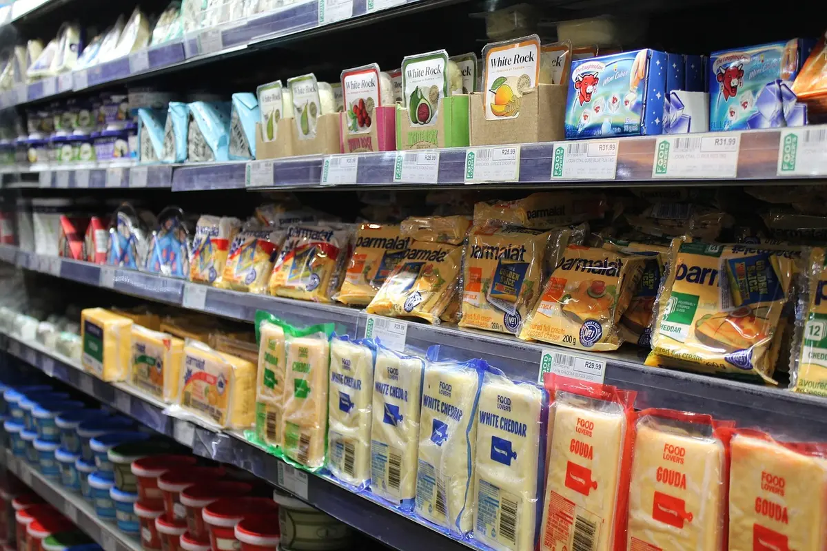 Vendeur montrant l'étiquette d'un produit laitier sur un étal en plein jour