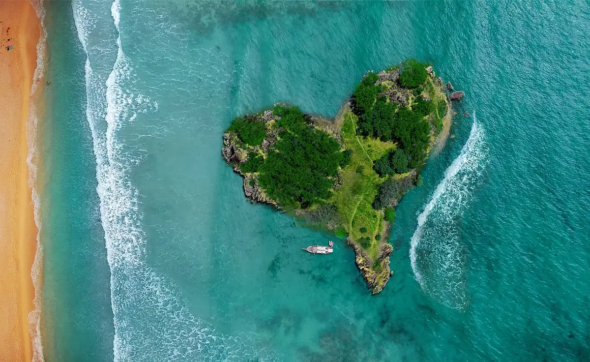 Vue aérienne d'une île tropicale montrant côtes, lagon et végétation