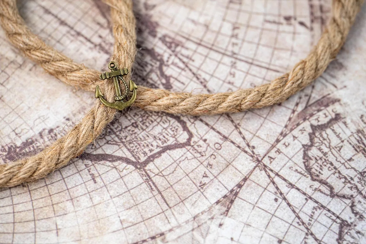 Voyageur préparant son voyage avec cartes et ordinateur près d'une fenêtre ensoleillée