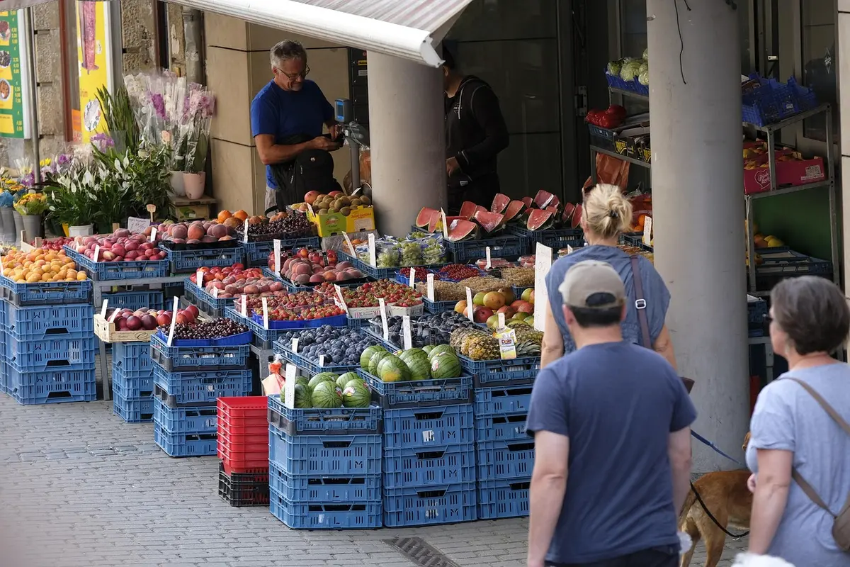 Petit commerce local animé en journée, mains échangeant paiement et produit