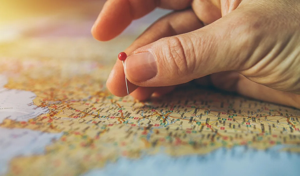 Personne planifiant un itinéraire avec une carte de Paris sur une table