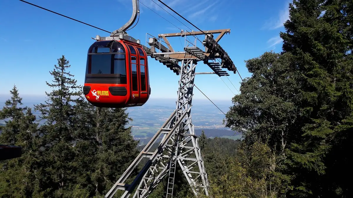 Chemin montant depuis une station de télécabine avec panneaux et randonneurs