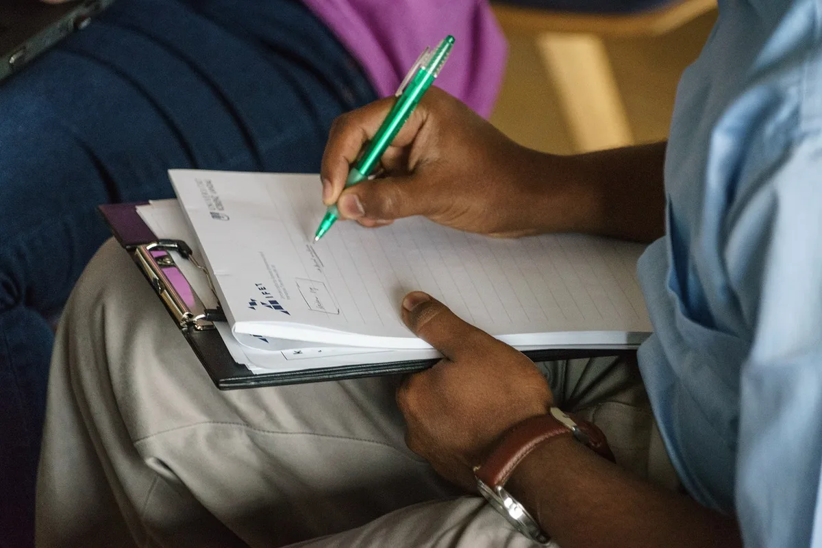 Billets de shilling tanzanien posés sur une table avec des mains à proximité