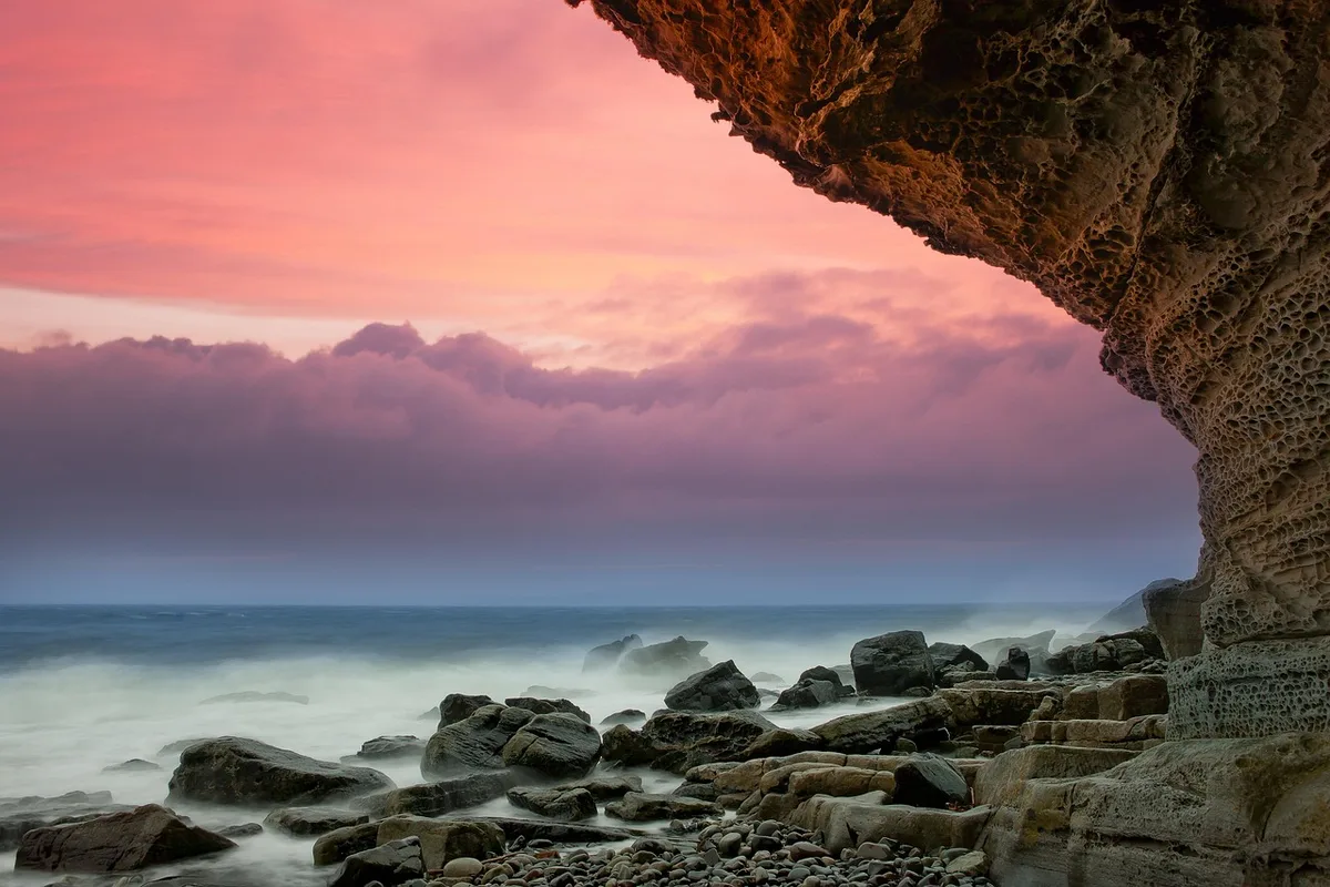 Falaises dorées de l’Algarve et une petite embarcation près d’une grotte marine