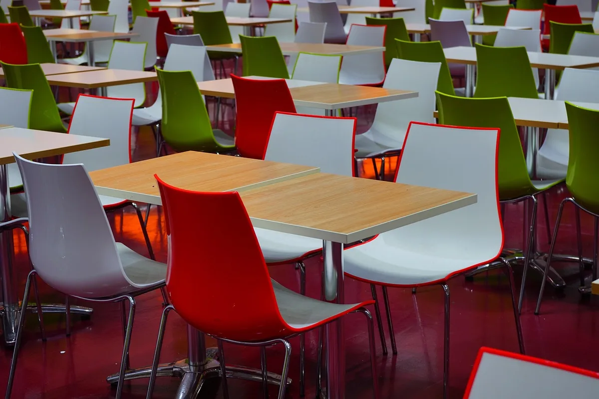 Salle à manger commune d'un hôtel en journée avec tables et chaises prêtes